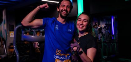 Happy couple in sportswear posing confidently at a gym, showing fitness enthusiasm.